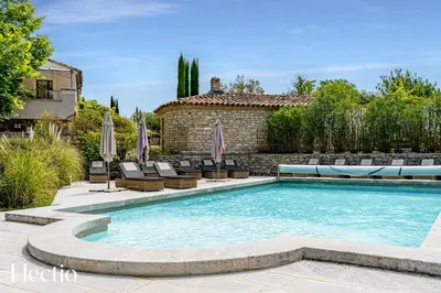 a swimming pool in a yard with chairs and a building at Résidence Les Petitons in Oppède
