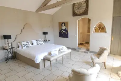 a bedroom with a large bed and a clock on the wall at Clos De La Fontaine in Cabrières-dʼAvignon