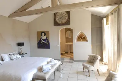a bedroom with a large bed and a clock on the wall at Clos De La Fontaine in Cabrières-dʼAvignon
