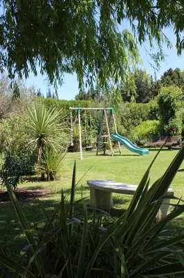 a playground with a bench and a swing at Gîtes maisons de vacances Domaine la Chamade Carpentras in Carpentras