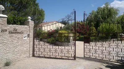 an iron gate in a garden with flowers at Gîtes maisons de vacances Domaine la Chamade Carpentras in Carpentras
