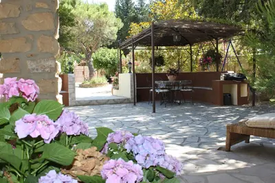a patio with a table and some pink flowers at Gîtes maisons de vacances Domaine la Chamade Carpentras in Carpentras