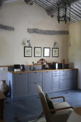 a kitchen with white cabinets and a sink and a chair at Le Mas Les Eydins in Bonnieux