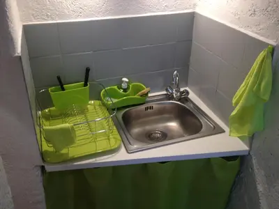 a kitchen sink with a green basket next to it at Appartement L'Atypique in Pertuis