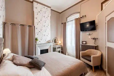 a bedroom with a bed and a chair and a television at Hôtel de Charme Le Provence in Salon-de-Provence