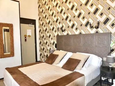 a bedroom with a large bed with a wooden wall at Hôtel de Charme Le Provence in Salon-de-Provence