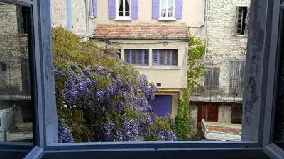 a window view of a building with purple flowers at Hotel Belvue in Sault-de-Vaucluse