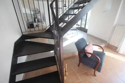 a black spiral staircase in a living room with a chair at Les Guillaume Rey in Oppède