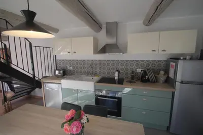 a kitchen with blue cabinets and a table with flowers on it at Les Guillaume Rey in Oppède
