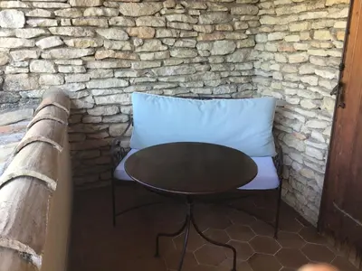 a table and a chair in front of a stone wall at Le Verger in Gordes