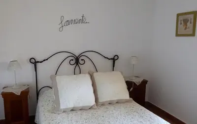 a bed with two pillows and a sign on the wall at Le Verger in Gordes
