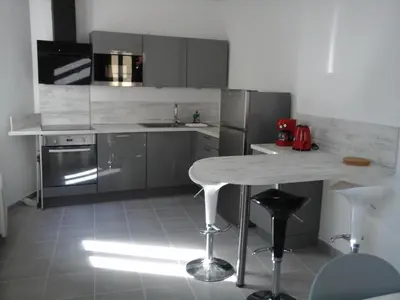 a kitchen with a table and stainless steel appliances at Colombe in LʼIsle-sur-la-Sorgue