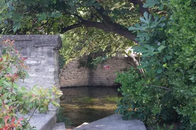 an archway in a brick wall next to a river at Colombe in LʼIsle-sur-la-Sorgue