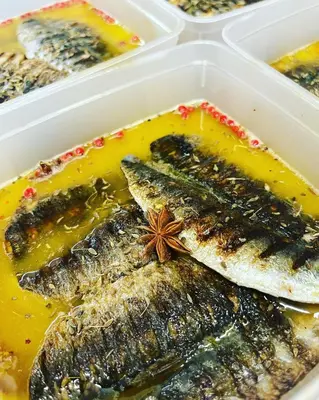 a plastic container filled with fish in a yellow sauce at Bar des Amis in Villars