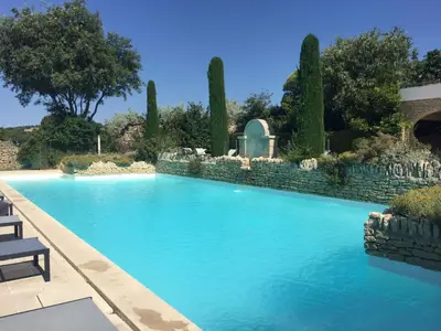 a swimming pool in a yard with a stone wall at Bastidon la Cicada in Gordes