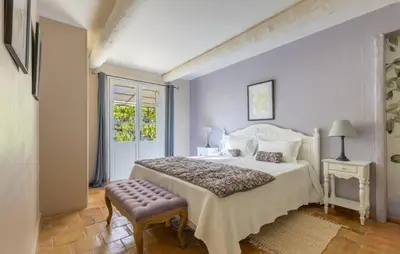a white bedroom with a bed and a window at Le Chant du Coeur in Roussillon