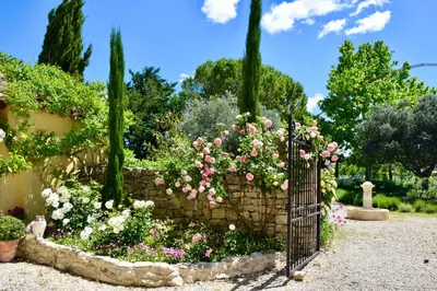 a garden with pink and white flowers and a stone fence at Bastide Saint-Didier in Saint-Didier