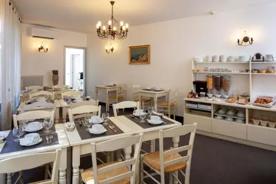 a dining room with tables and chairs and a kitchen at Hôtel Le Mozart in Aix-en-Provence