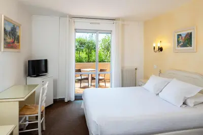 a hotel room with a bed and a desk and a window at Hôtel Le Mozart in Aix-en-Provence
