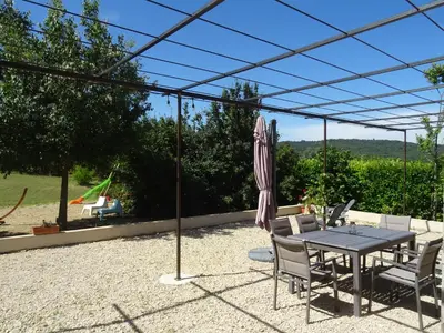 a patio with a table and chairs and an umbrella at Campagne Cérès in Le Puy-Sainte-Réparade