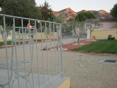 a metal gate in front of a yard with mountains at Le Jardin des Tourterelles in Robion en Luberon