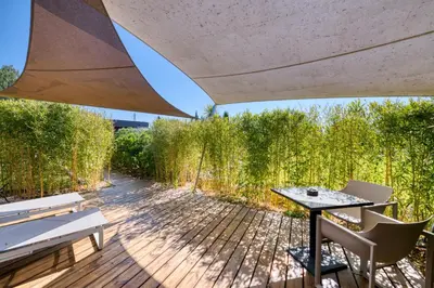 a patio with a table and chairs on a wooden deck at Mas des Cigales in Eygalières