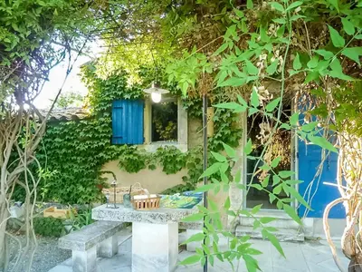 a picnic table in a garden with a blue window at Maison charmante à Oppède avec piscine partagée in Oppède