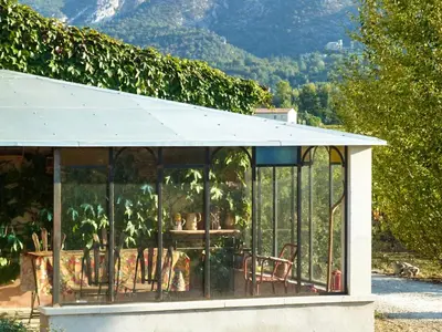 a glass house with a roof with a table and chairs at Maison charmante à Oppède avec vue sur la montagne in Oppède