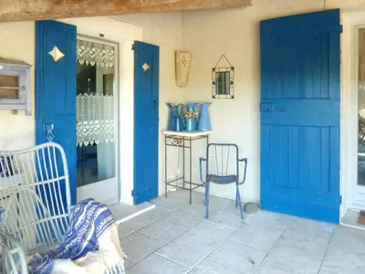 a porch with blue doors and a chair and a table at Appartement accueillant avec piscine à Oppède 70 m², vue montagne in Oppède