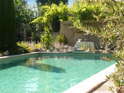 a swimming pool in a yard with a chair and trees at Appartement accueillant avec piscine à Oppède 70 m², vue montagne in Oppède