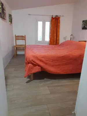 a bedroom with a bed with a red blanket and a chair at Gîte chez Cécile à Lagnes, aux portes du Luberon in Lagnes