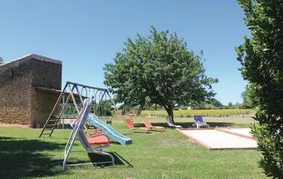 a playground with a slide and chairs in the grass at Cozy Home In Pernes Les Fontaines in Pernes-les-Fontaines