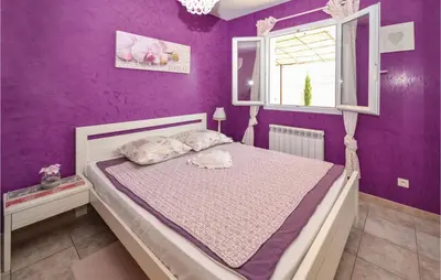 a bedroom with a bed with purple walls and a window at Beautiful Home In Maubec in Maubec