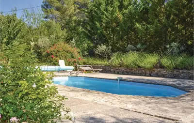 a swimming pool in a yard with a stone wall at Amazing Home In Crillon Le Brave in Crillon-le-Brave