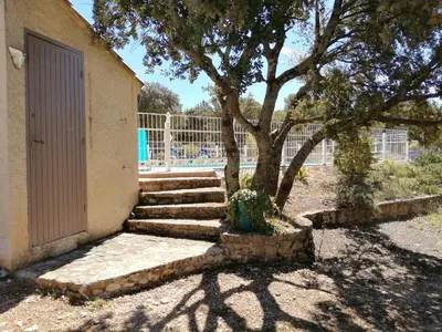 a tree and stairs next to a building with a door at L'oustau des euses in Bédoin