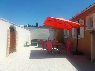 a table with red chairs and a red umbrella at Maison de charme avec piscine privée à Velleron in Velleron