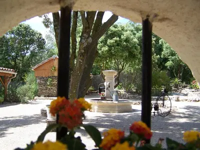 a view of a fountain in a yard with flowers at Les Florides in LʼIsle-sur-la-Sorgue