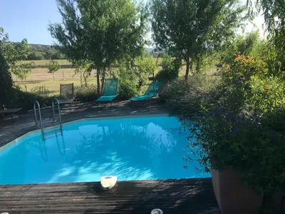 a swimming pool with blue chairs and trees at Lou mas li Pitchoun 