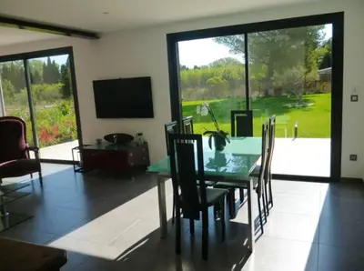 a dining room with a table and chairs and a television at Villa charmante à Eyragues avec piscine privée in Eyragues