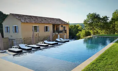 a swimming pool with lounge chairs next to a house at Mas Ste Hélène in Céreste