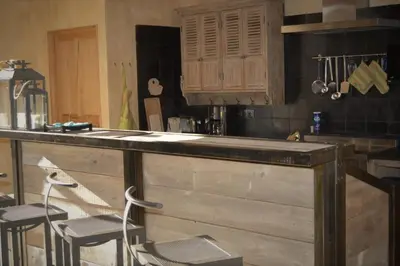 a kitchen with a wooden counter with two stools at Mas Ste Hélène in Céreste
