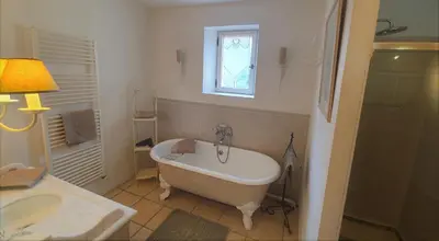 a bathroom with a tub and a sink and a window at Côté Provence in Le Thor