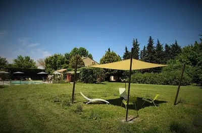 a yellow umbrella and two chairs in a field at Côté Provence in Le Thor