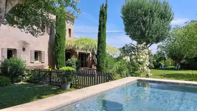 a swimming pool in front of a house with a fence at Le Mas Des Bardes in Pernes-les-Fontaines