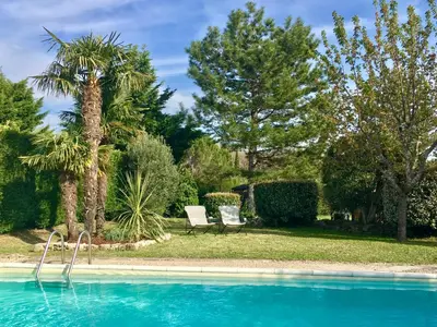 a swimming pool with two chairs and palm trees at Le Petit Bastidon - Private pool - Gordes in Gordes