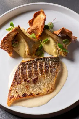 a white plate with two pieces of fish and vegetables at Domaine la Pierre Blanche in Eygalières