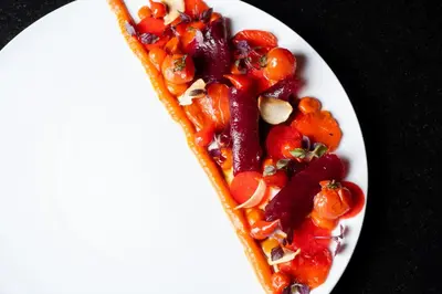 a white plate of food with vegetables on a table at Domaine la Pierre Blanche in Eygalières