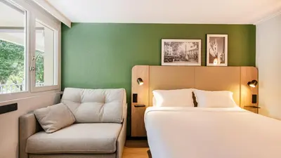 a bedroom with a bed and a chair at Campanile Prime - Aix-en-Provence Sud - Pont de l'Arc in Aix-en-Provence