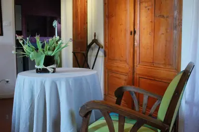a table with a vase of flowers and two chairs at Les Volets Bleus Provence in Salon-de-Provence