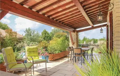 a patio with chairs and tables and a wooden pergola at 3 Bedroom Stunning Home In Gordes in Gordes